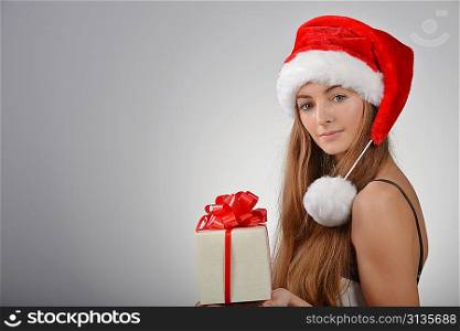 Beautiful young woman in santa claus hat holding gift box