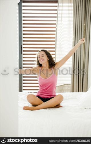 Beautiful young woman in the bedroom waking up and stretch her arms