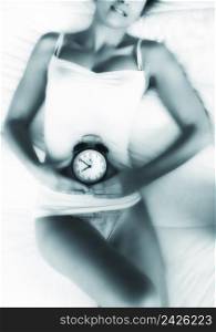 Beautiful young woman in underwear holding a clock