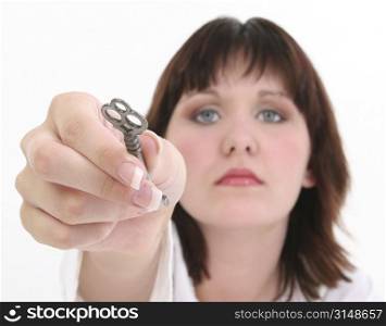 Beautiful young woman in white against white holding out skeleton key.Beautiful hands, manicured nails.