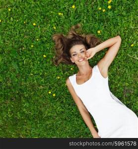 beautiful young woman in white dress lying on grass. young woman in white dress lying on grass