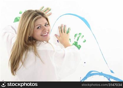 Beautiful young woman in white painting on wall. Shot in studio.