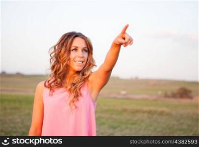 Beautiful young woman indicating something in the countryside with beautiful light