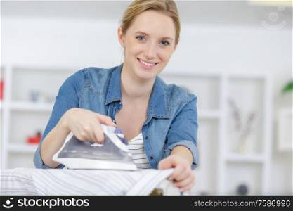 beautiful young woman is ironing clothes