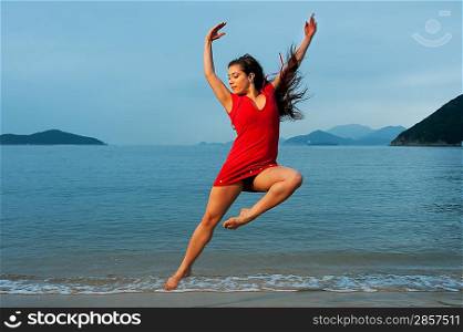 Beautiful young woman jumping in the sea
