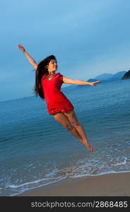 Beautiful young woman jumping in the sea