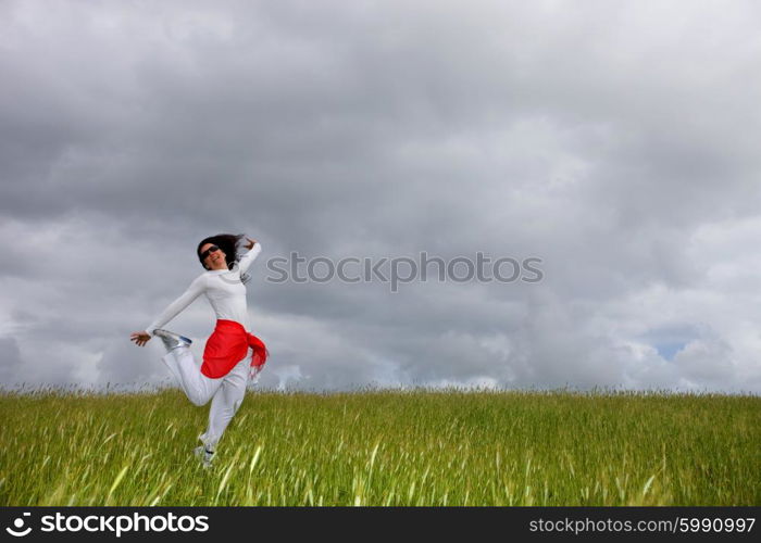 beautiful young woman jumping on field with a red scarf
