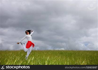 beautiful young woman jumping on field with a red scarf