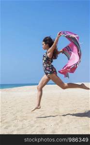 Beautiful young woman jumping with beach wrap