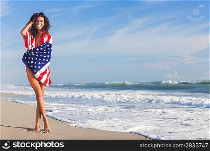 Beautiful young woman laughing wearing bikini and wrapped in American flag towel on a sunny beach