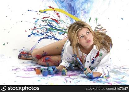 Beautiful young woman laying in paint covered studio. Paint splattered on walls, floor, model. Shot in studio over &acute;white&acute;. :)