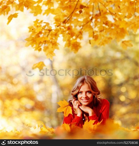 Beautiful young woman laying on yellow leaves in autumn park. Woman laying in autumn park