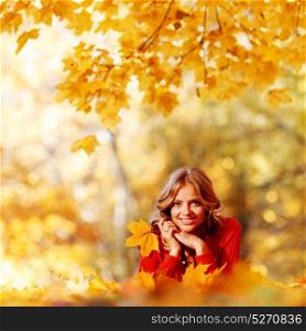 Beautiful young woman laying on yellow leaves in autumn park. Woman laying in autumn park
