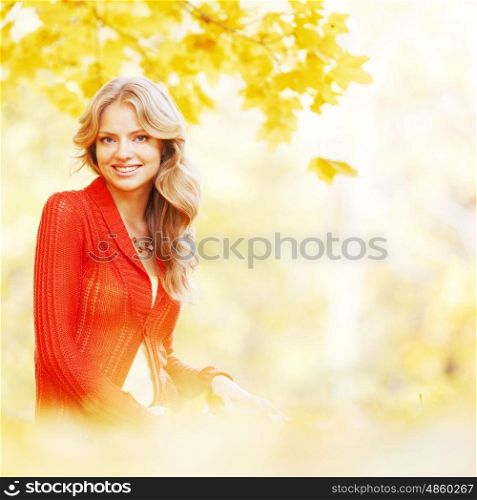 Beautiful young woman laying on yellow leaves in autumn park. Woman sitting in autumn park
