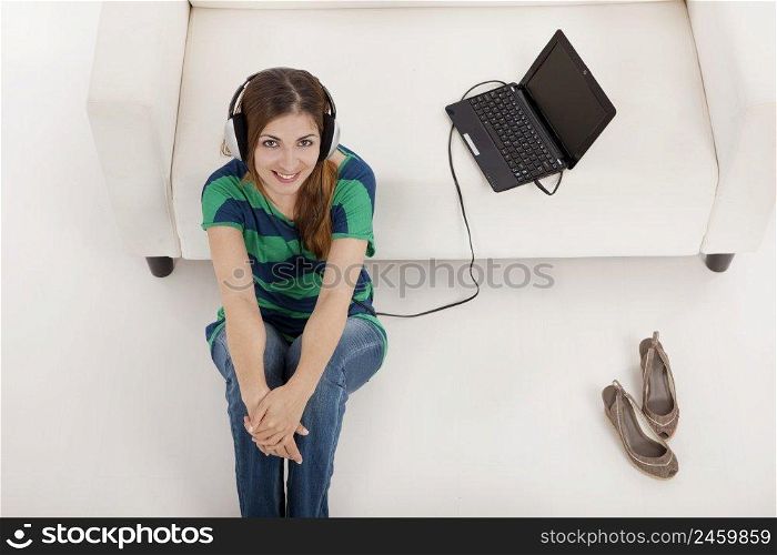 Beautiful young woman listen music on a laptop, isolated on white