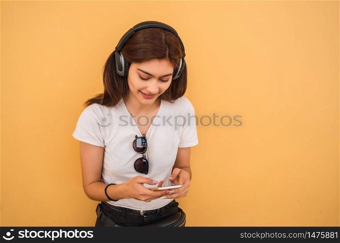 Beautiful young woman listening music and using her smartphone. Technology concept. Urban scene.