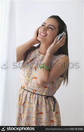 Beautiful young woman listening to headphones at home
