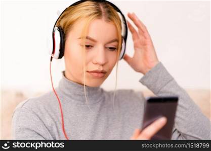 Beautiful young woman listening to the music headphones mobile phone smart at home application