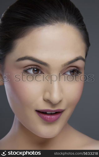 Beautiful young woman looking away over colored background