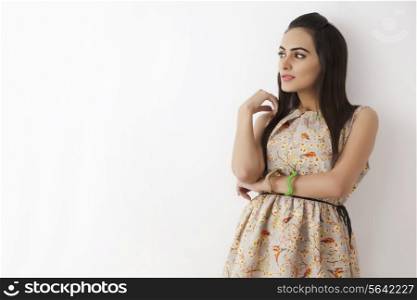 Beautiful young woman looking away over white background