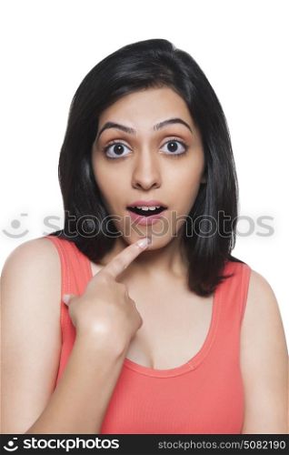 Beautiful young woman looking surprised with finger on chin