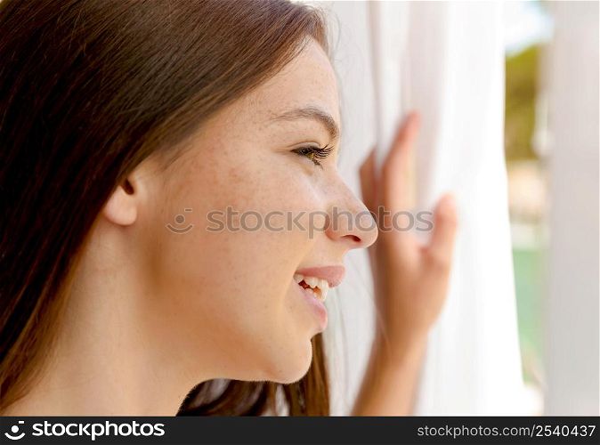Beautiful young woman looking through window
