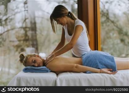 Beautiful young woman lying and having neck massage in spa salon during winter season