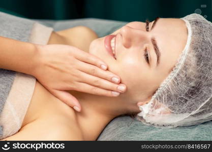 Beautiful young woman lying and touching face skin after cosmetic procedures in spa. Woman lying and touching face skin