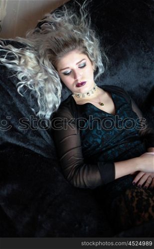 Beautiful young woman lying on a velvet throw