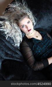 Beautiful young woman lying on a velvet throw