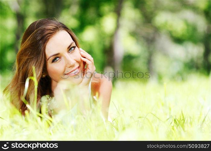 Beautiful young woman lying on grass enjoying nature. Young woman lying on grass