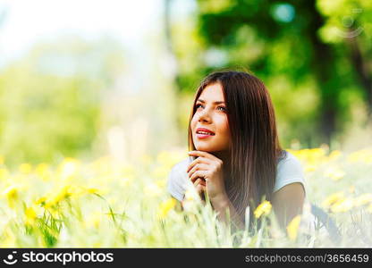 Beautiful young woman lying on grass with flowers