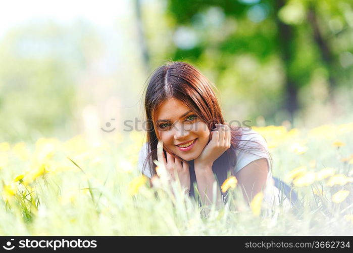 Beautiful young woman lying on grass with flowers