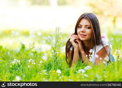 Beautiful young woman lying on grass with flowers