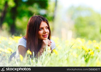 Beautiful young woman lying on grass with flowers
