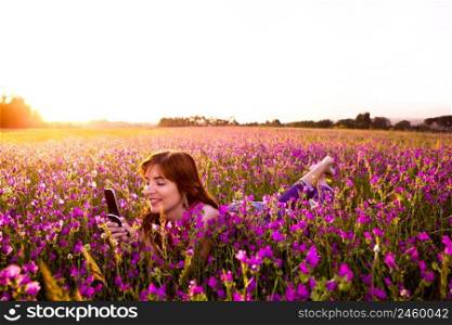 Beautiful young woman lying on the nature and talking at cellphone 