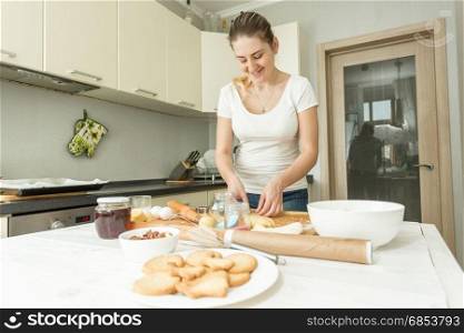 Beautiful young woman making dough on kitchen at home
