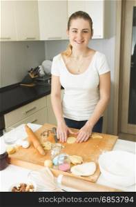 Beautiful young woman making dough on kitchen at home