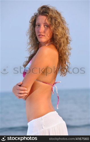 beautiful young woman near the sea at sunset
