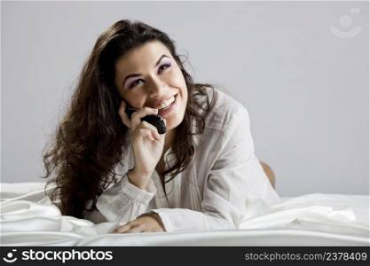 Beautiful young woman on bed making a phone call
