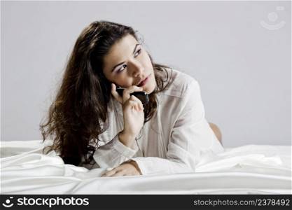 Beautiful young woman on bed making a phone call