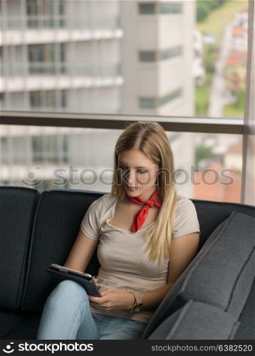 beautiful young woman on sofa at home surfing internet using tablet computer