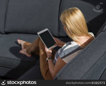 beautiful young woman on sofa at home surfing internet using tablet computer