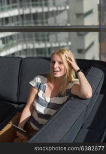 beautiful young woman on sofa at home surfing internet using tablet computer