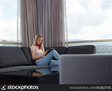 beautiful young woman on sofa at home surfing internet using tablet computer