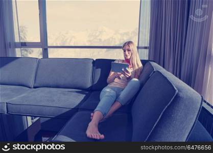 beautiful young woman on sofa at home surfing internet using tablet computer. young woman on sofa at home surfing web