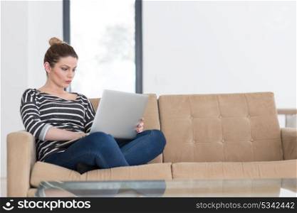 beautiful young woman on sofa at home websurfing internet with laptop computer