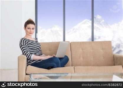 beautiful young woman on sofa at home websurfing internet with laptop computer