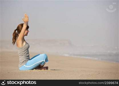 Beautiful young woman on the beach doing yoga exercises