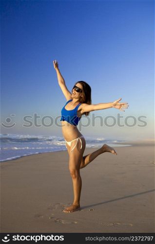 Beautiful young woman on the beach with arms open